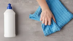 Čištění povrchu hadříkem a čistícím prostředkem na šedé ploše